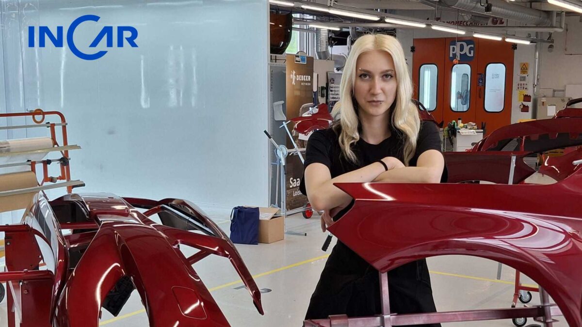 Woman in a black shirt leaning on red car body parts in a bright auto workshop, with a blue INCAR logo on the wall behind her.